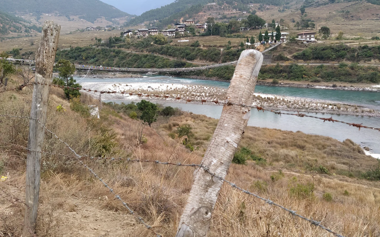 A prayer-flag-covered suspension footbridge crossing a Himalayan river in Bhutan — original photo by goFLY founder Mahabub Alam Razu, December 2019