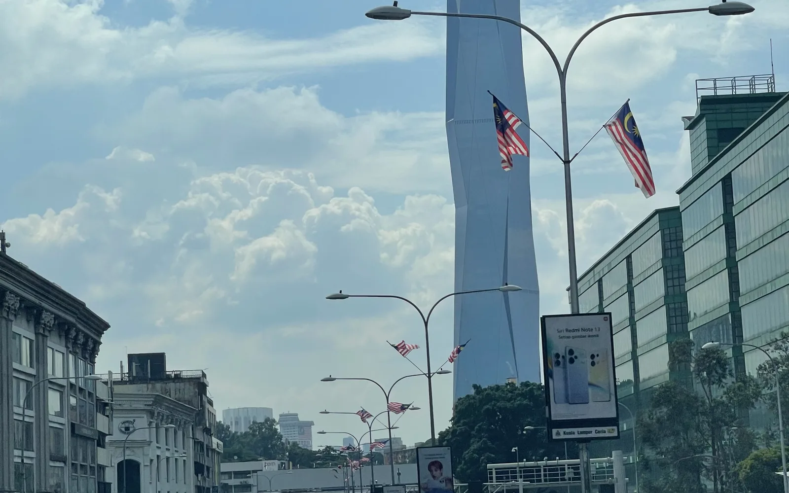 A Kuala Lumpur street with a skyscraper and Malaysian flags overhead, Malaysia — photo by goFLY founder Mahabub Alam Razu, August 2024