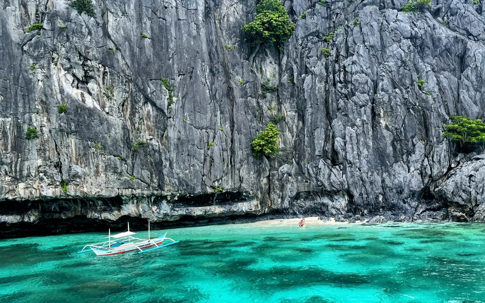Emerald lagoon water beneath limestone cliffs with an outrigger boat, El Nido, Palawan, Philippines — photo by goFLY founder Mahabub Alam Razu, August 2024