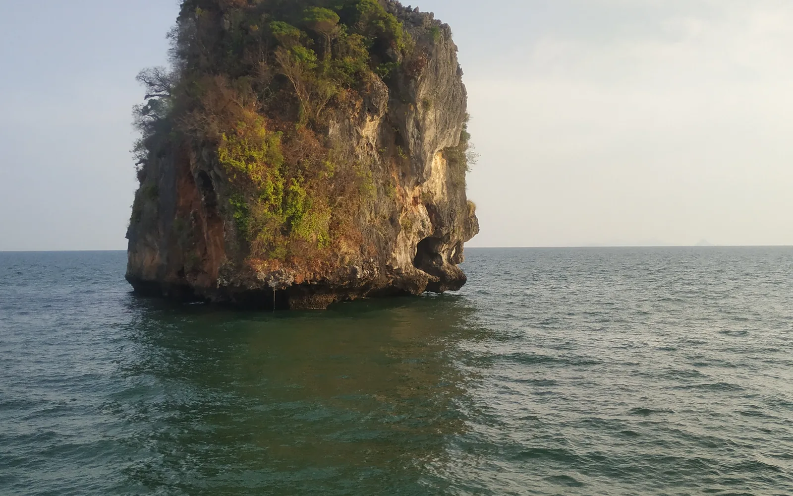 A lone limestone karst rock standing in the calm Andaman Sea off Krabi, Thailand — photo by goFLY founder Mahabub Alam Razu, March 2019