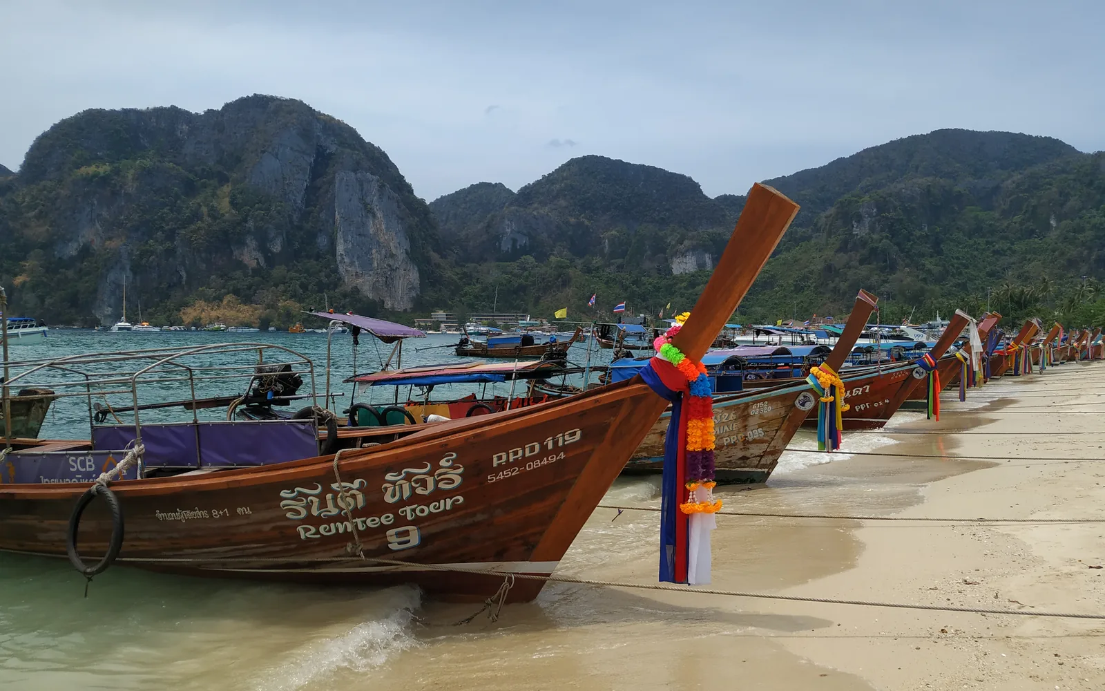 A longtail boat moored on a Phi Phi island beach with limestone cliffs behind, Thailand — photo by goFLY founder Mahabub Alam Razu, March 2019
