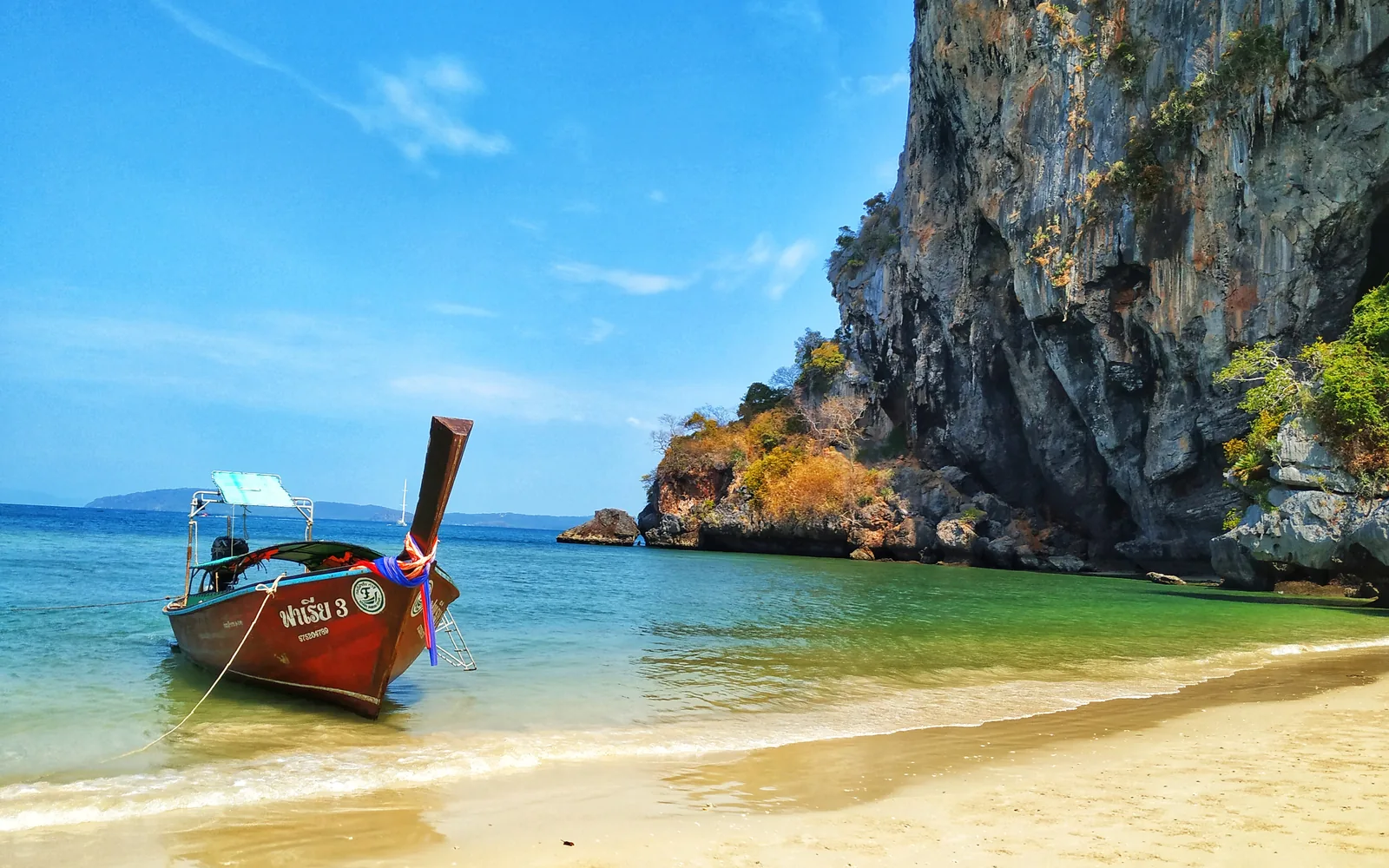 A longtail boat on Railay Beach beneath limestone cliffs, Krabi, Thailand — photo by goFLY founder Mahabub Alam Razu