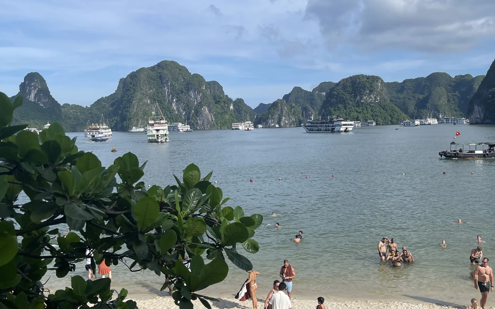 A beach below the limestone islands of Halong Bay with boats on the water, Vietnam — photo by goFLY founder Mahabub Alam Razu, August 2024